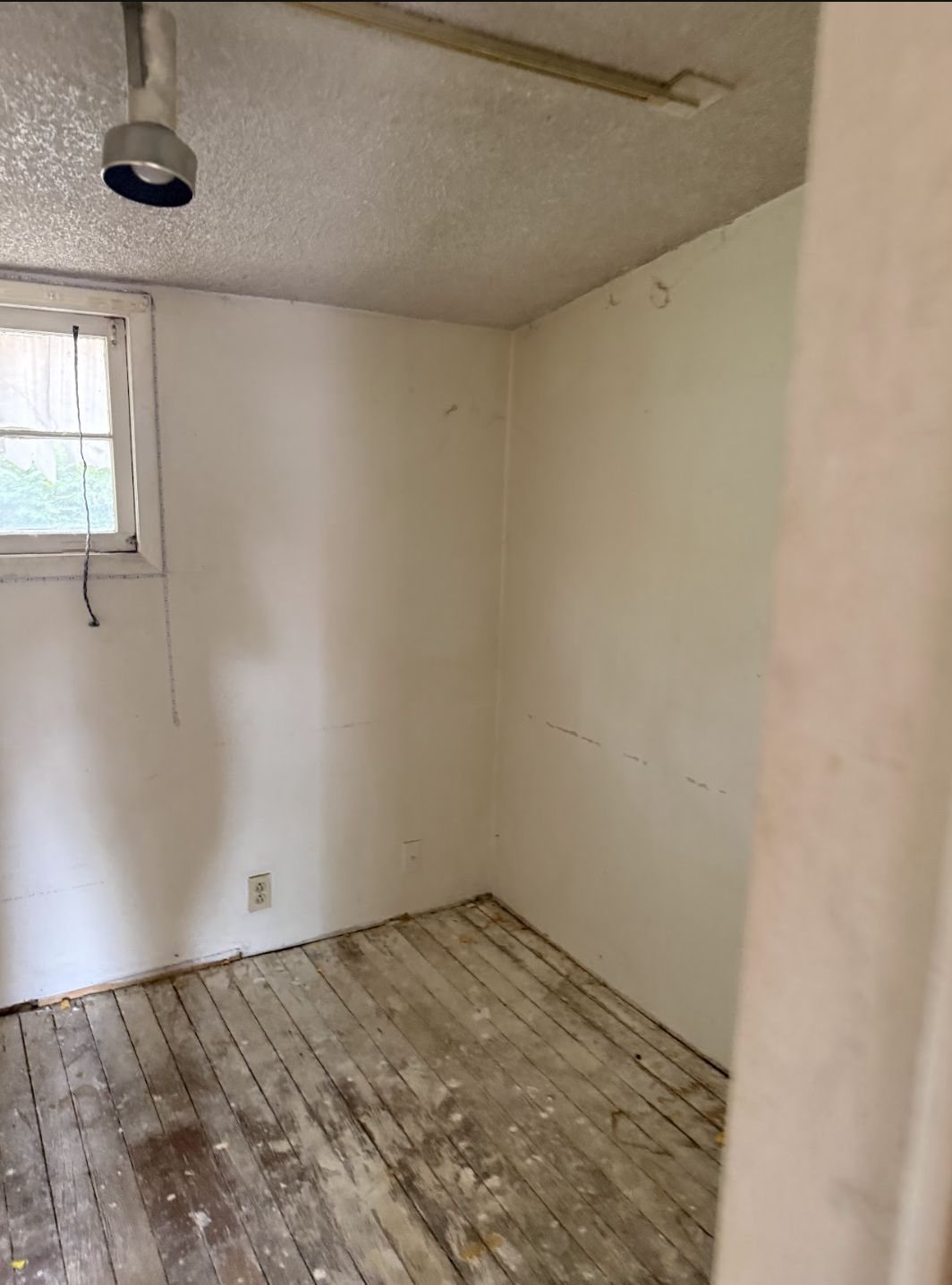 Unfinished interior room with worn floors and marked walls